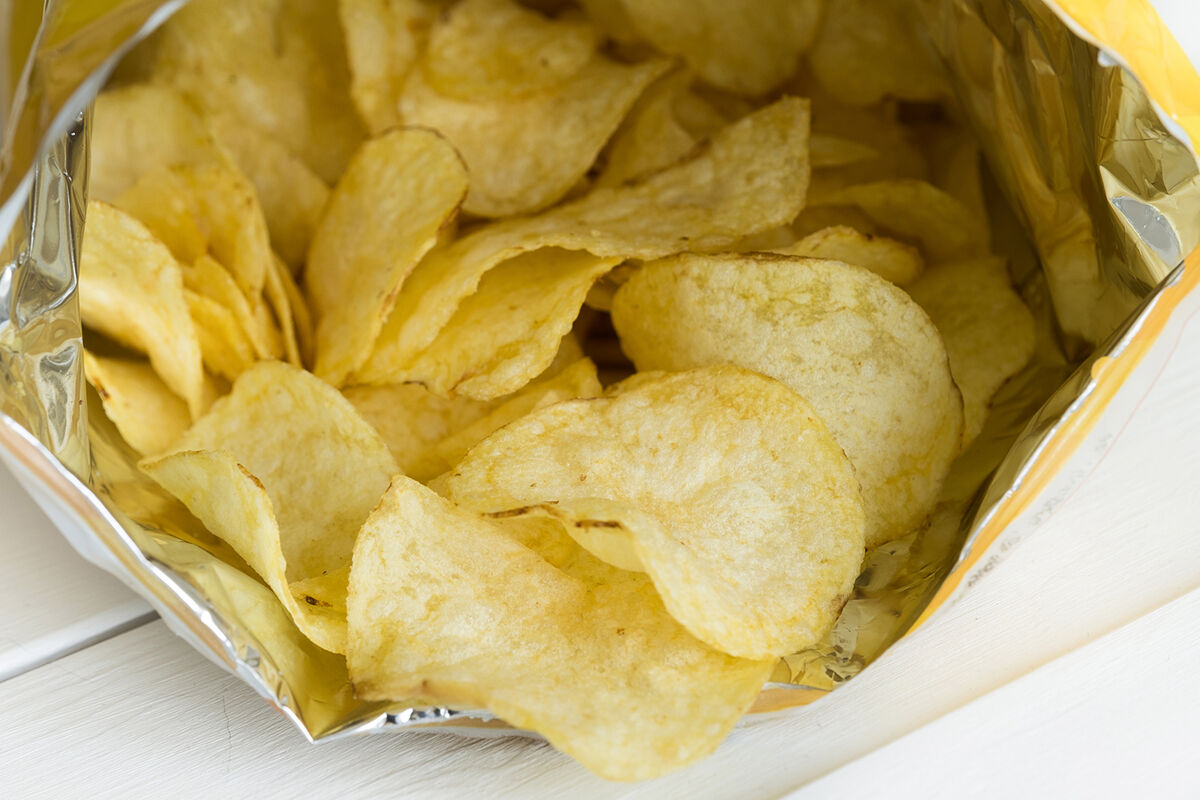 Crispy Fried Greasy Potato Chips fall out or are spilled out of the package