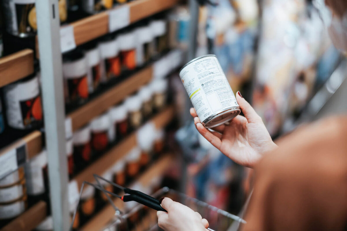 Woman holding a tin can and reading the nutritional label