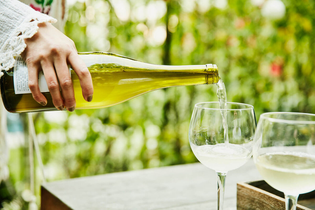 Woman pouring white wine into glasses