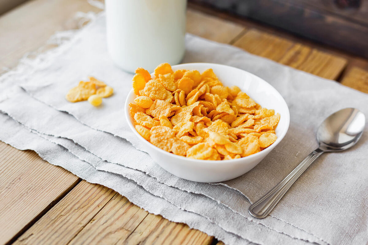 Tasty corn flakes in bowl with milk bottle