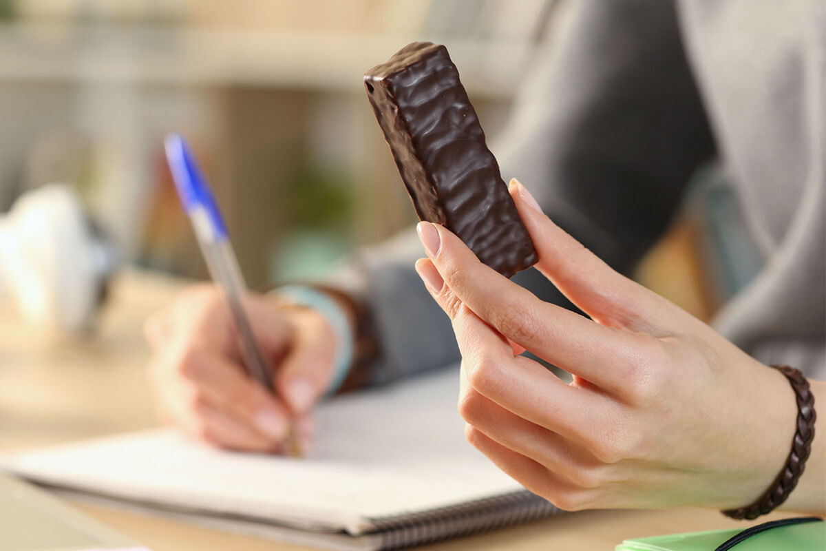 woman eating protein bar at desk