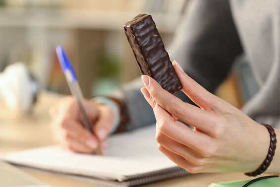 woman eating protein bar at desk