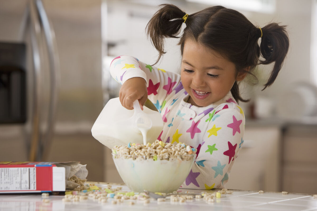 Little girl making  bowl of cereal