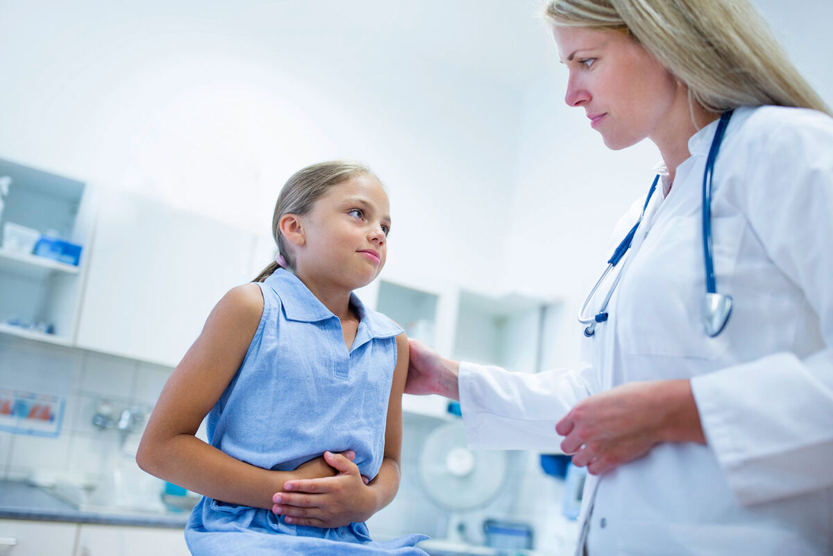 Girl with doctor clutching stomach