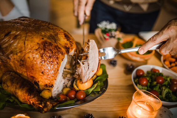 Close up of unrecognizable man carving roasted Thanksgiving turkey.