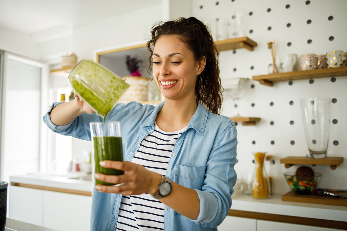 woman pouring a green smoothie