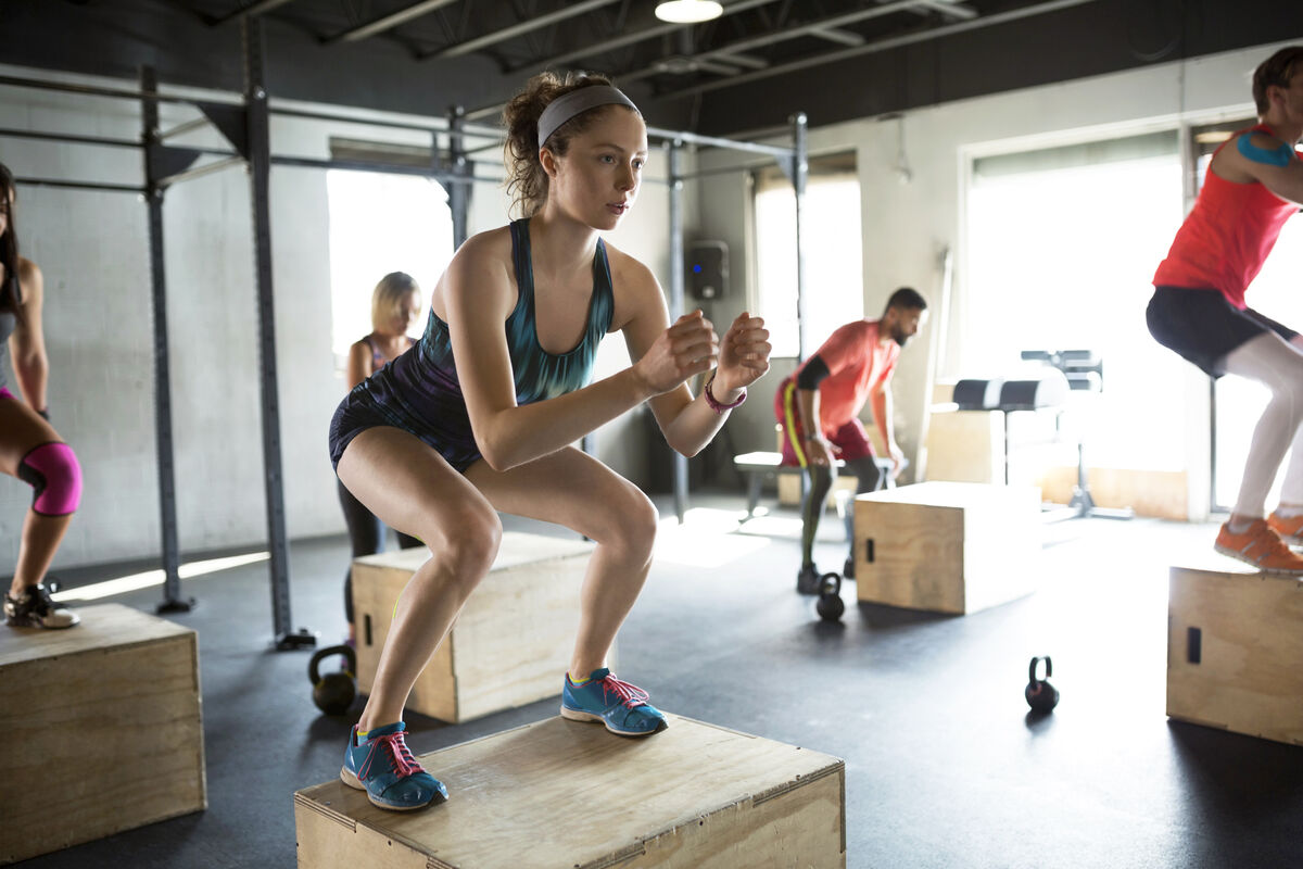 Woman jump squats in gym exercise class