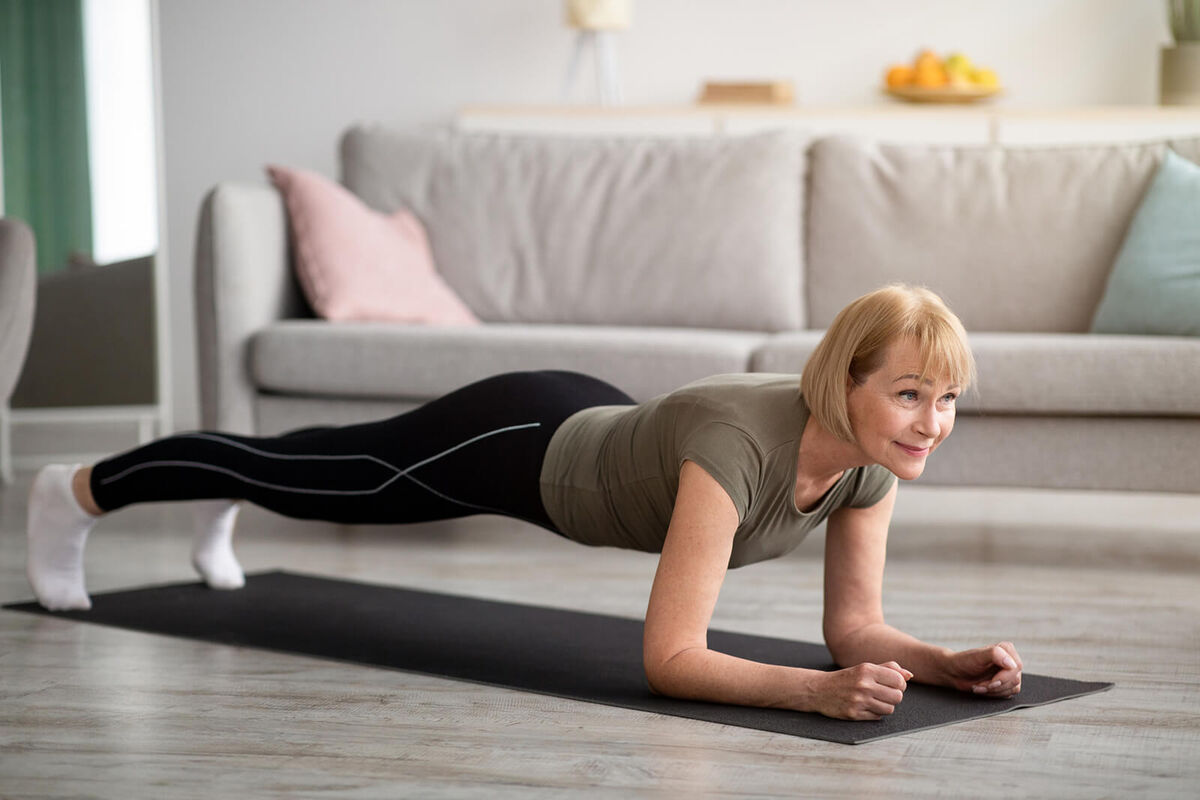 senior woman standing in elbow plank