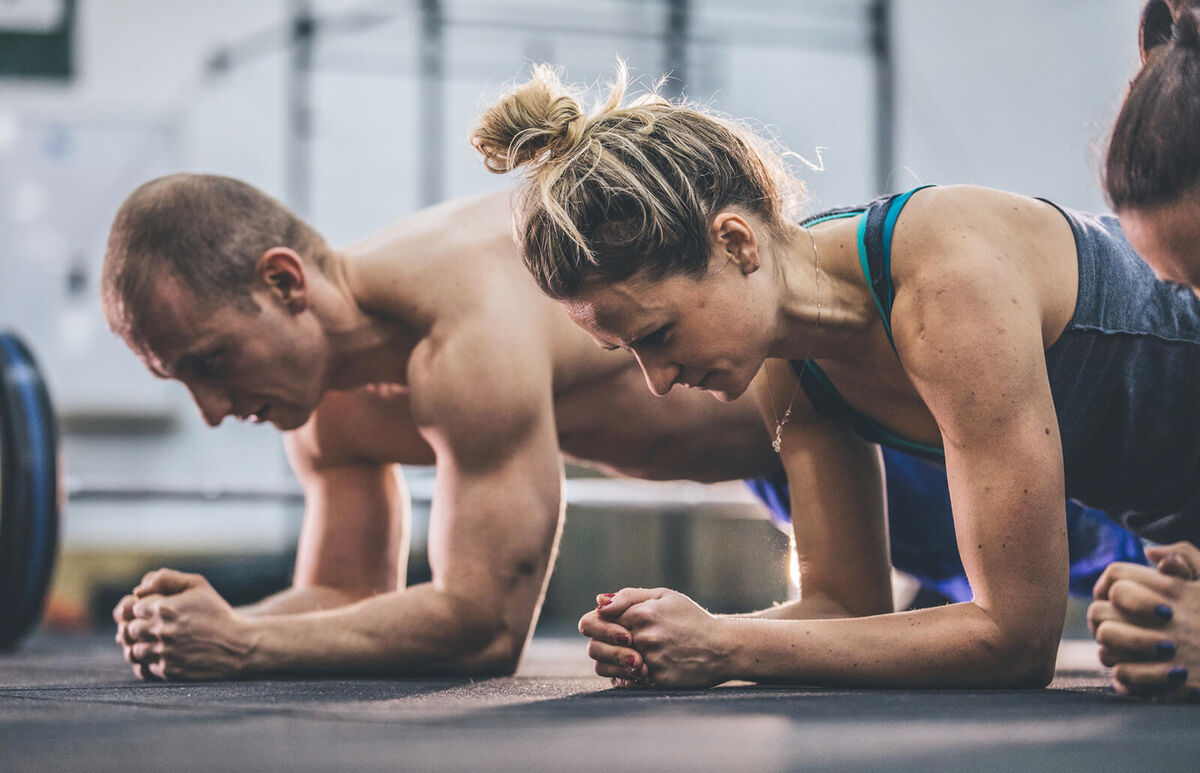 Man and woman doing plank exercises at the gym