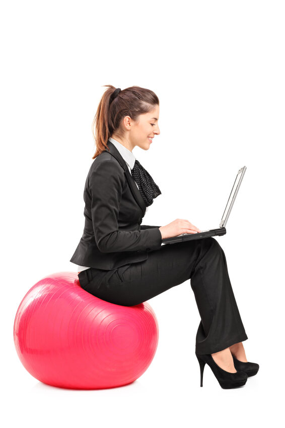 woman sitting on exercise ball in suit, typing