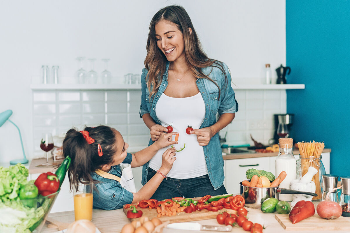 mother and daughter making vegetable smiley face