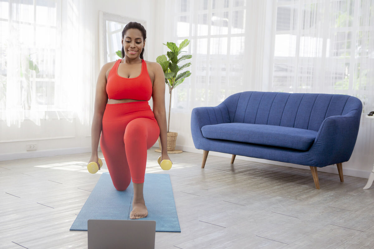 Woman in sportswear doing sports at home with laptop