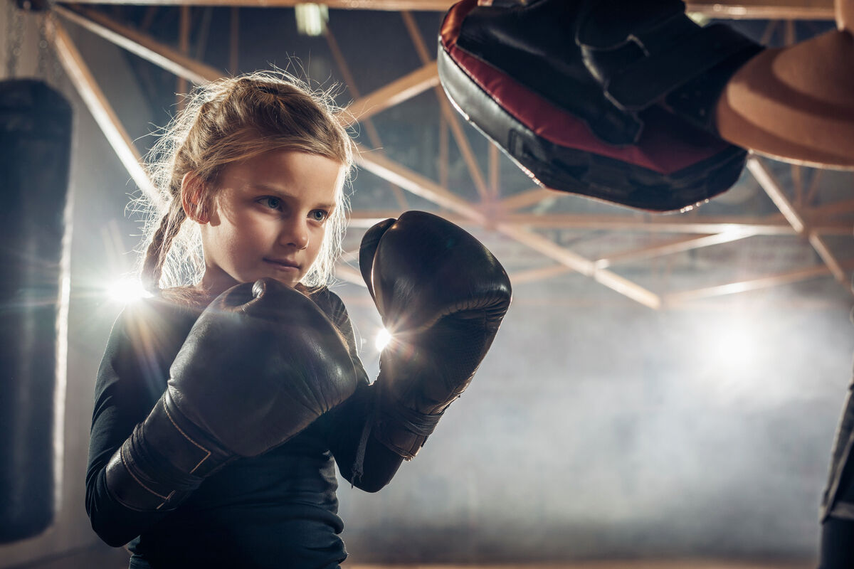 Small girl exercising boxing with coach in a gym