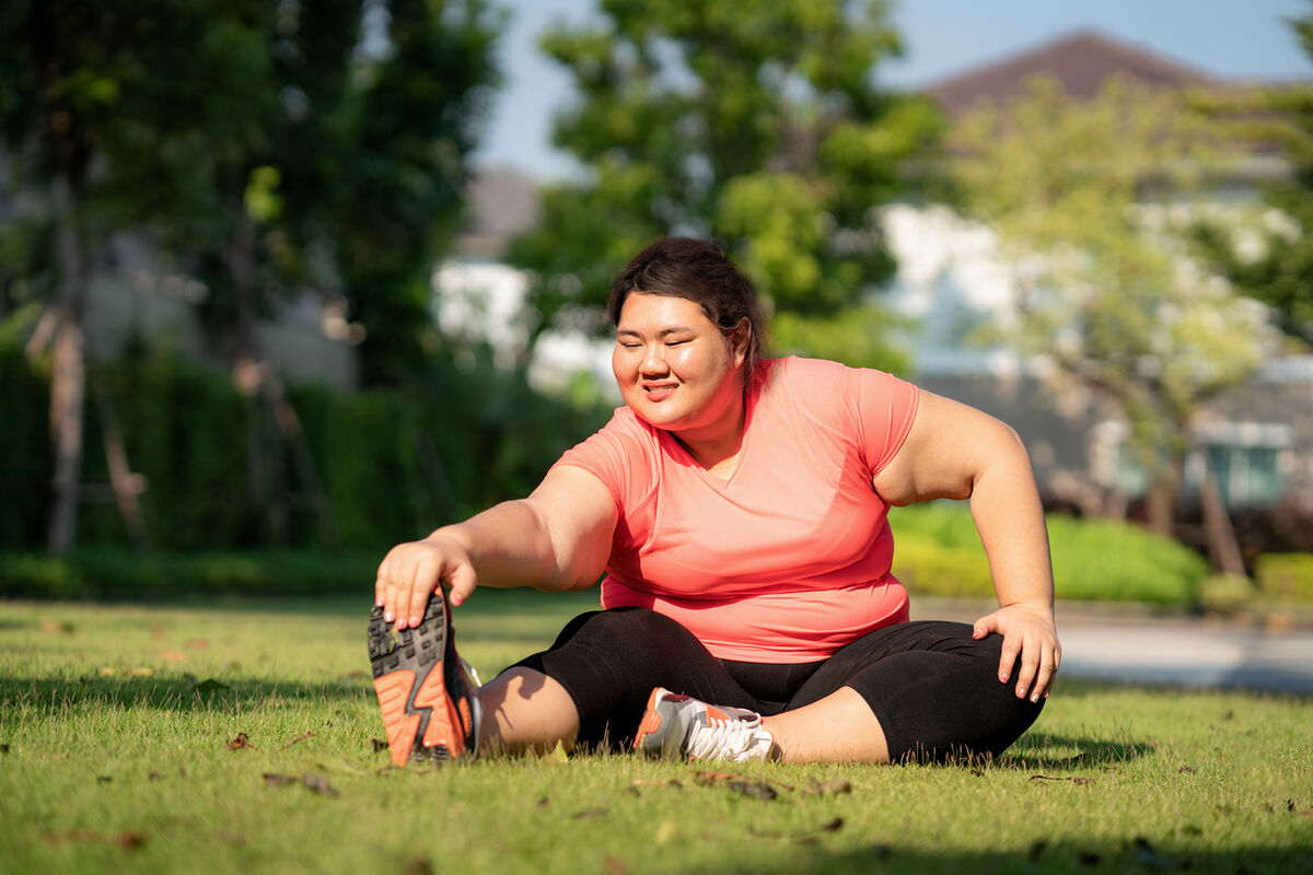 Overweight woman exercising in park, happy and smile in morning during sunlight