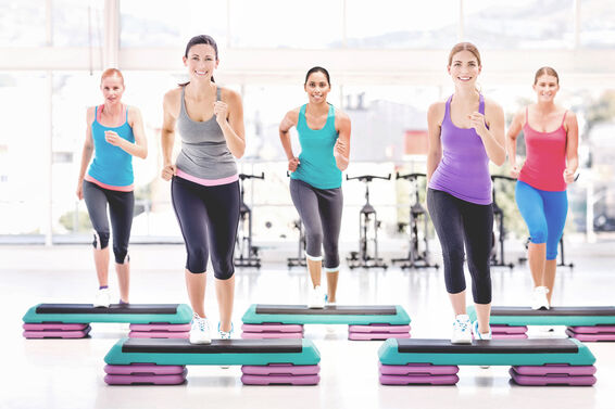 Fitness Class Doing Aerobics Exercise In Health Club