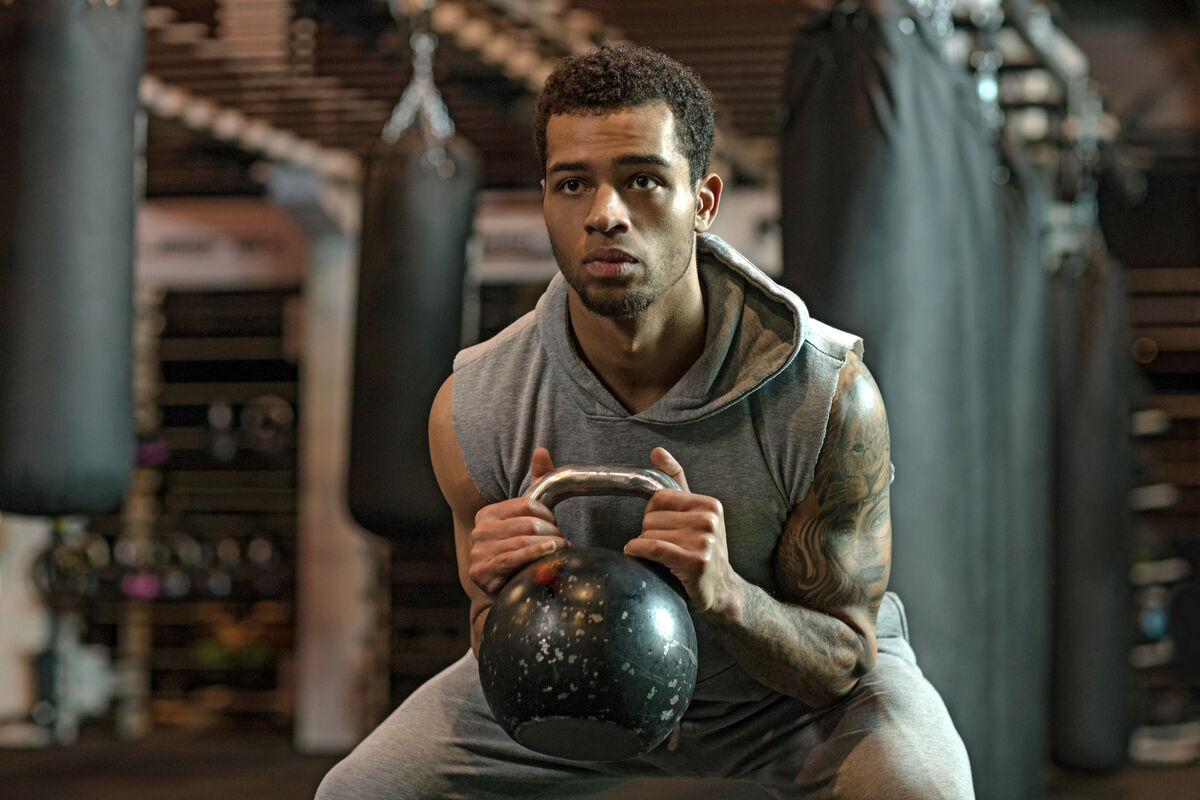 Young handsome Boxer Fighter training hard with a kettlebell in Gym Setting