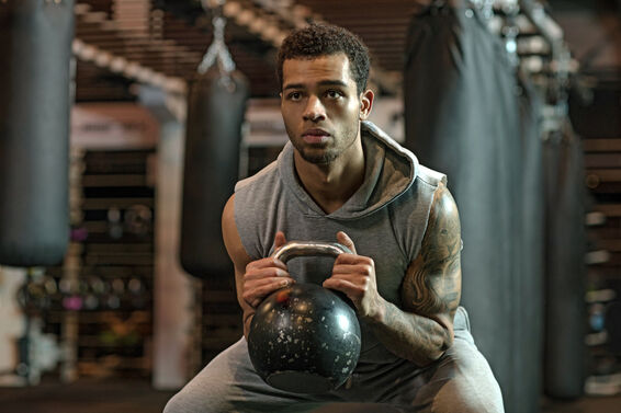 Young handsome Boxer Fighter training hard with a kettlebell in Gym Setting