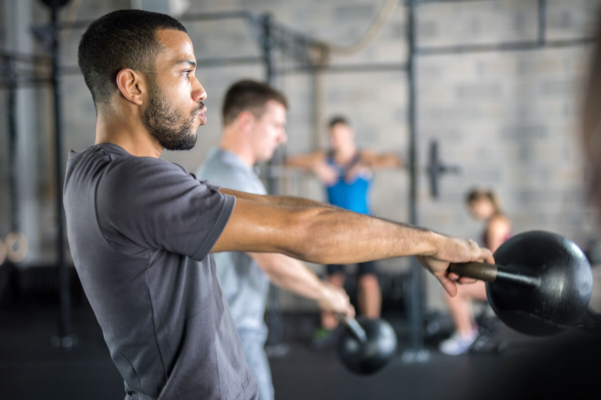 Men exercising with kettlebell in gym