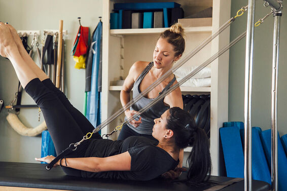 Woman and personal trainer using pilates reformer