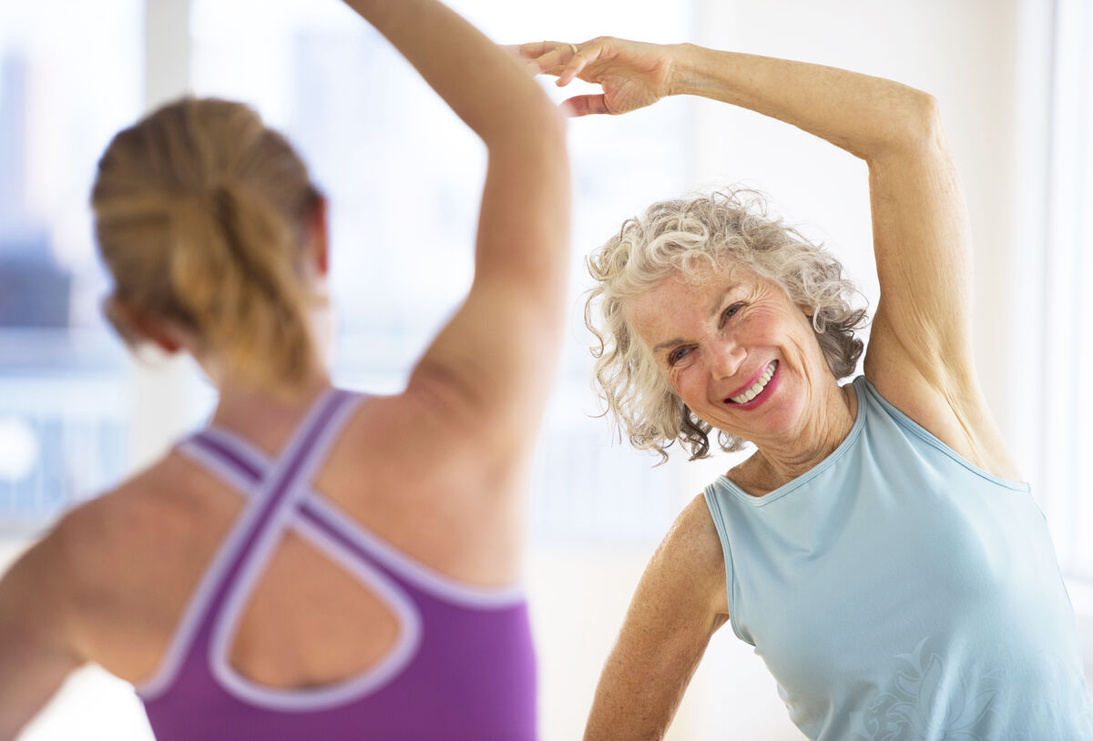 Senior woman with fitness instructor at gym - stock photo