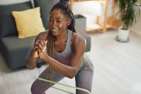 woman doing squats with resistance band on her around her legs at home