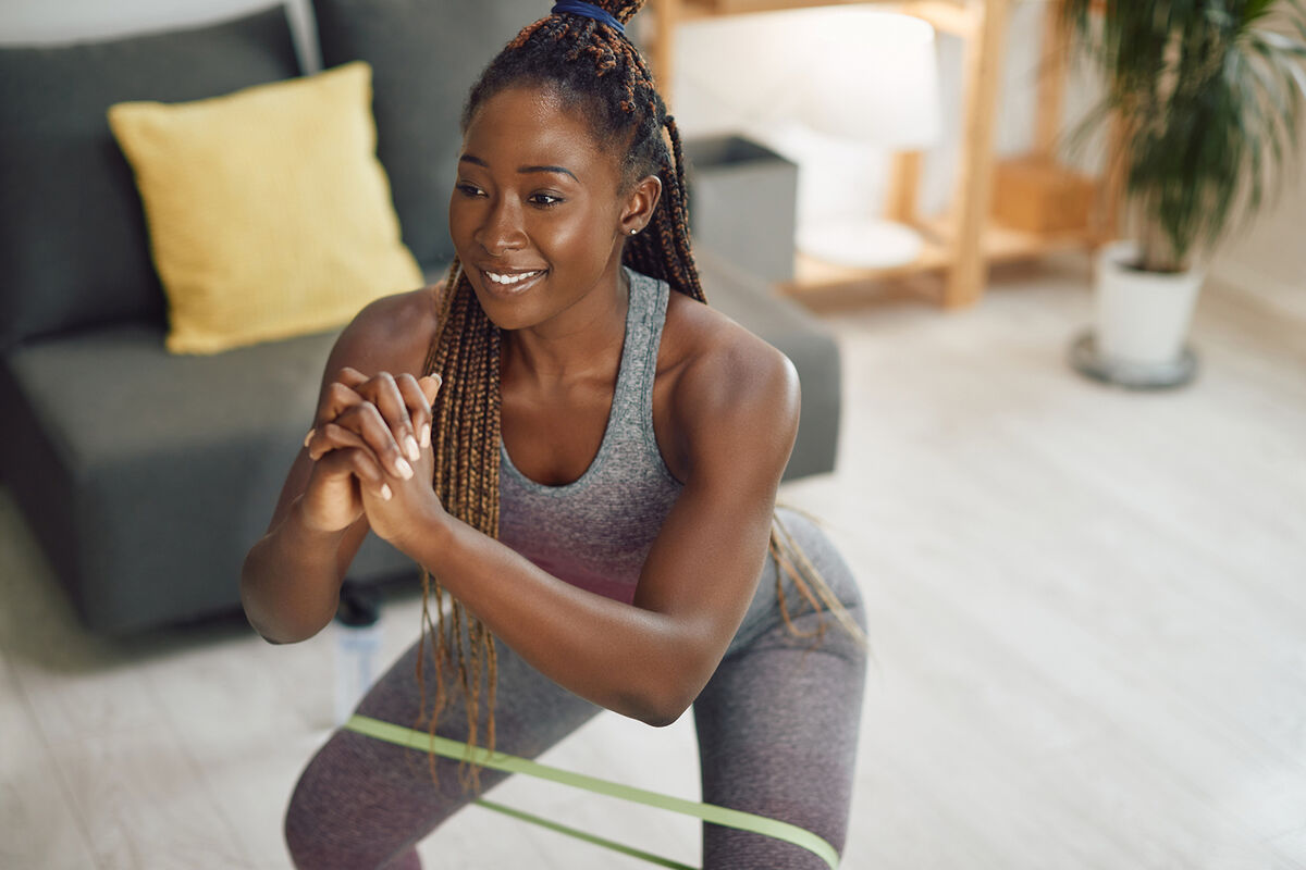 woman doing squats with resistance band on her around her legs at home