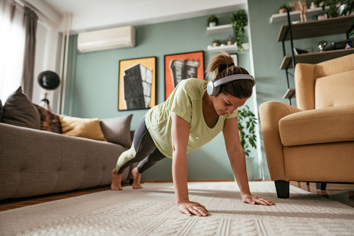 Adult woman exercising at home during quarantine, doing push ups