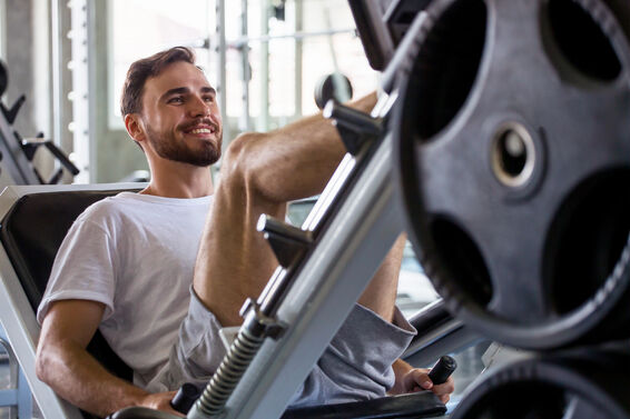 Man doing exercises with leg press machine in fitness gym