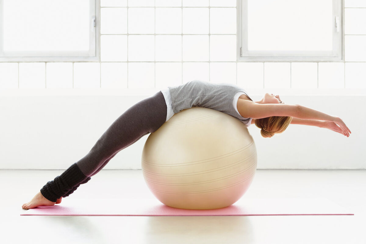 Young woman stretching on exercise ball