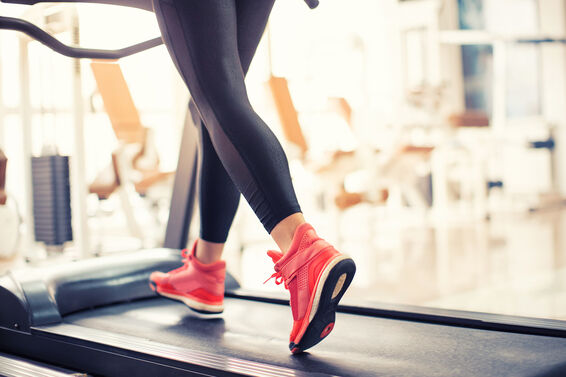Young woman running and exercising on treadmill in gym.