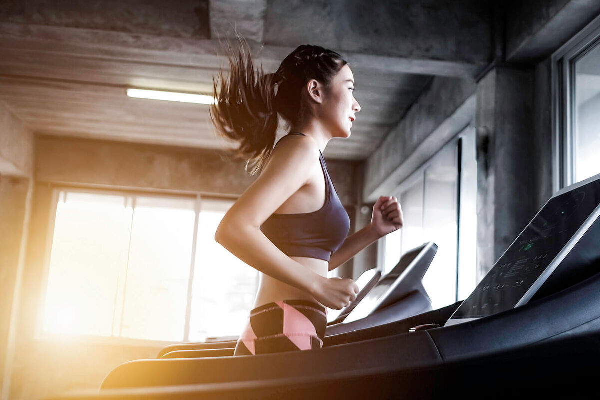 Young Woman Running On Treadmill At Gym