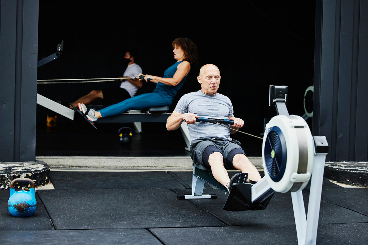 Mature man working out on rowing machine at outdoor gym