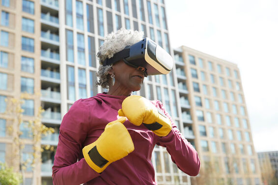 Senior woman wearing virtual reality headset while exercising in park