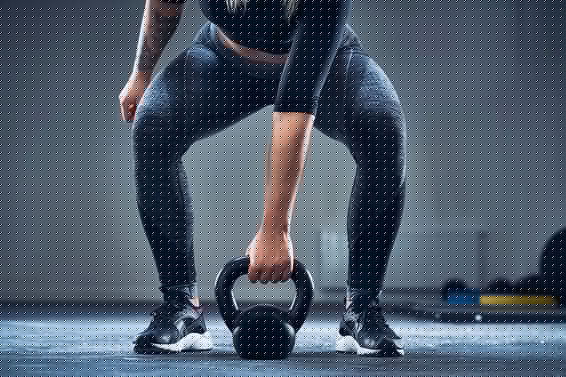 woman exercising with kettlebell at gym