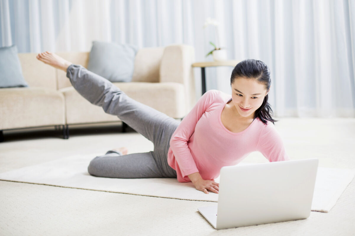 Young woman practicing yoga with laptop in living room