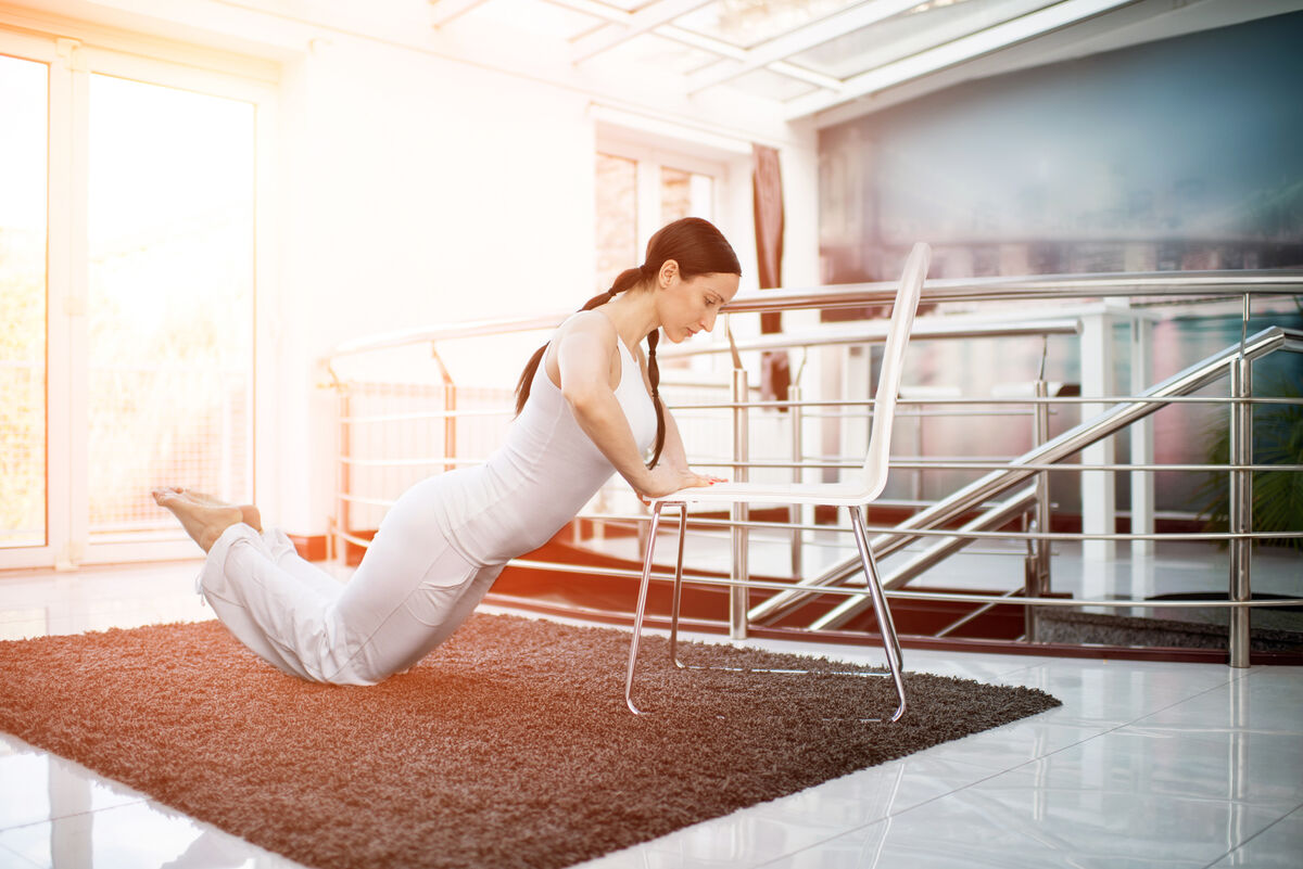 Woman doing chair push-ups at home