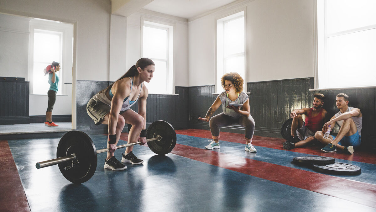 woman doing barbell clean . with spotter