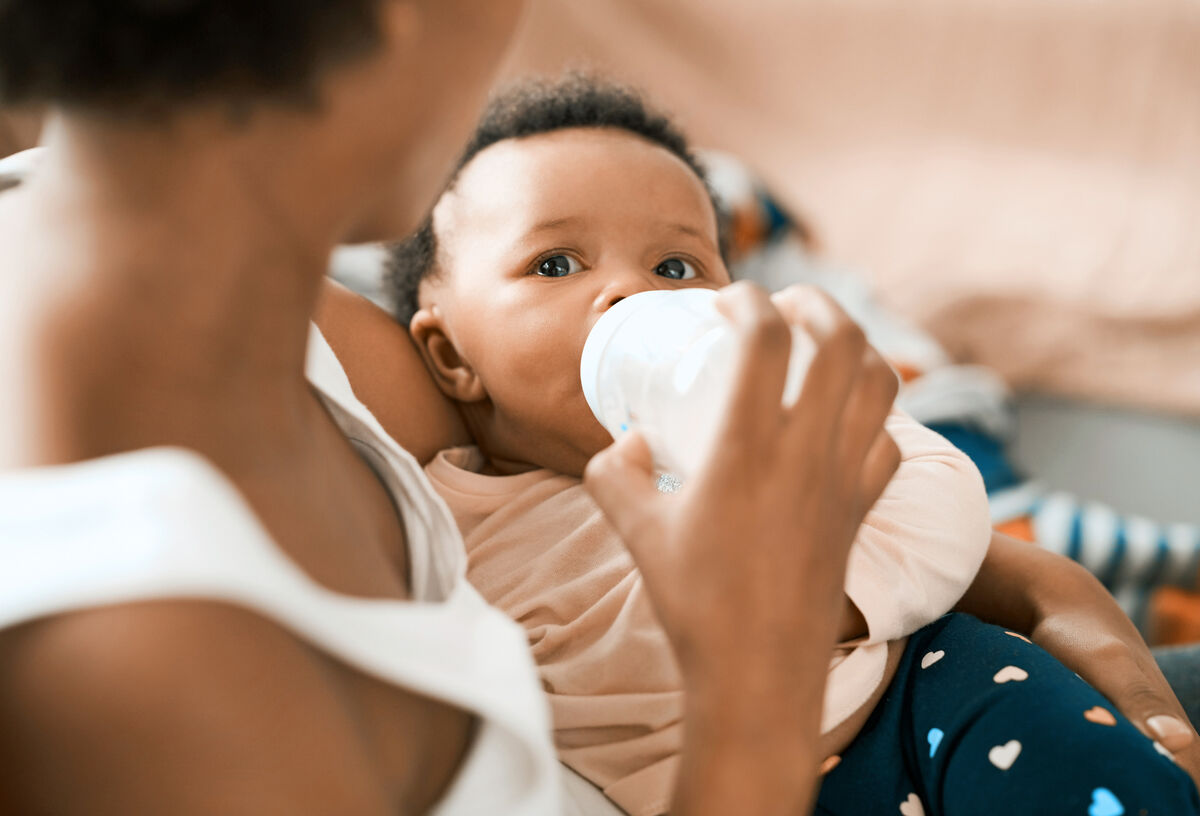 Mother feeding her adorable infant daughter at home