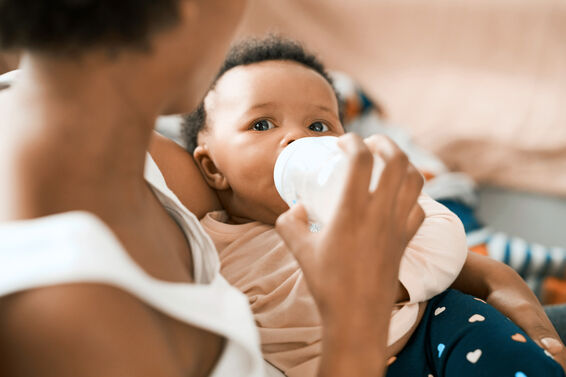 Mother feeding her adorable infant daughter at home
