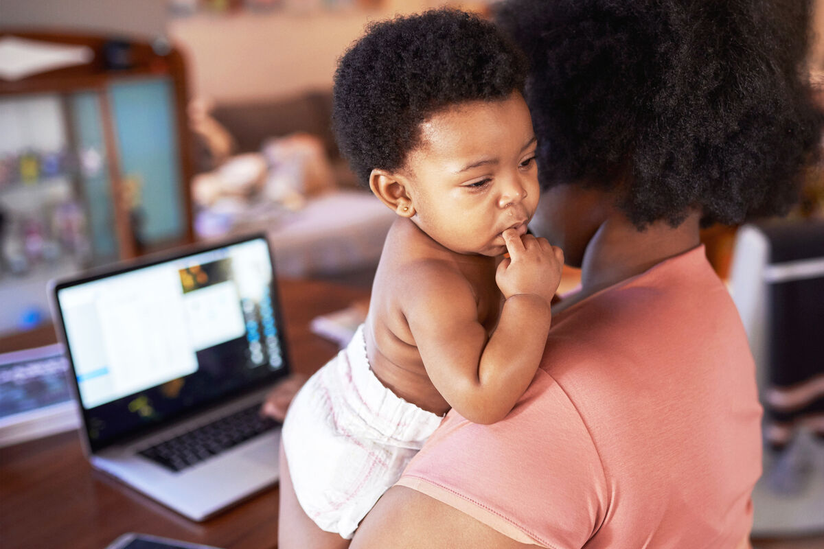 Woman on her laptop while holding her baby