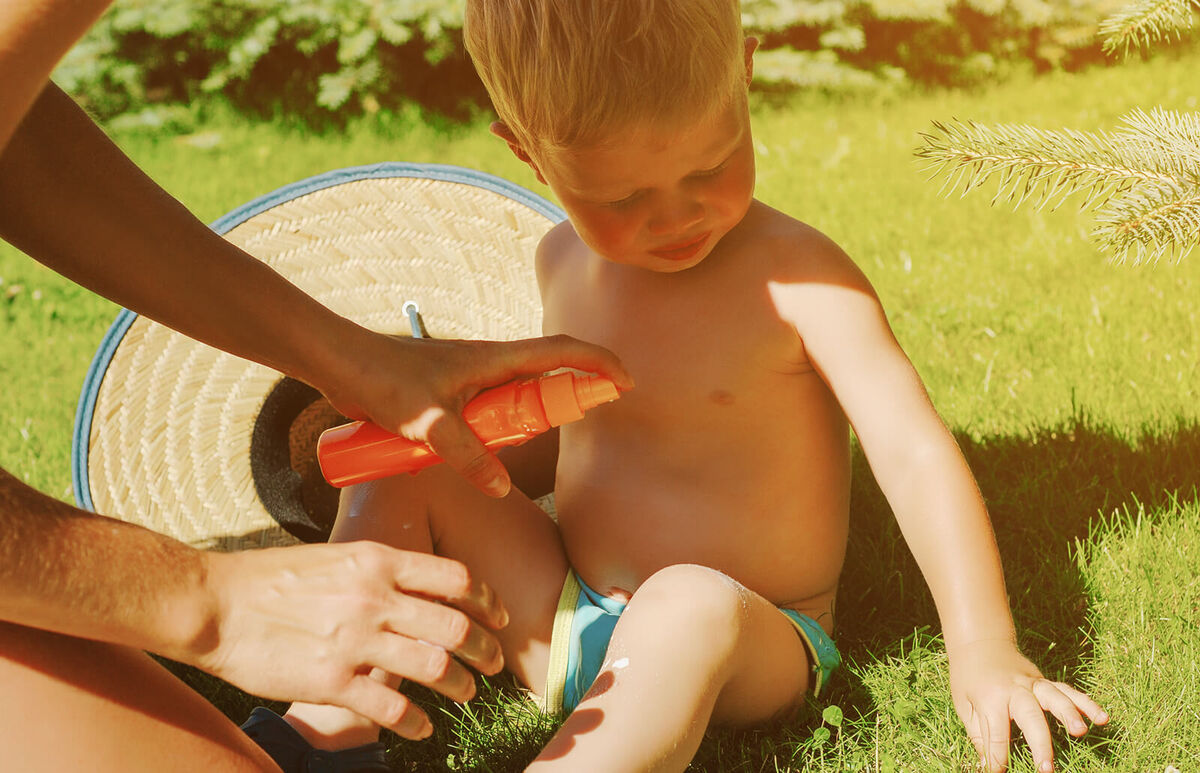 parent applying insect repellent spray on son