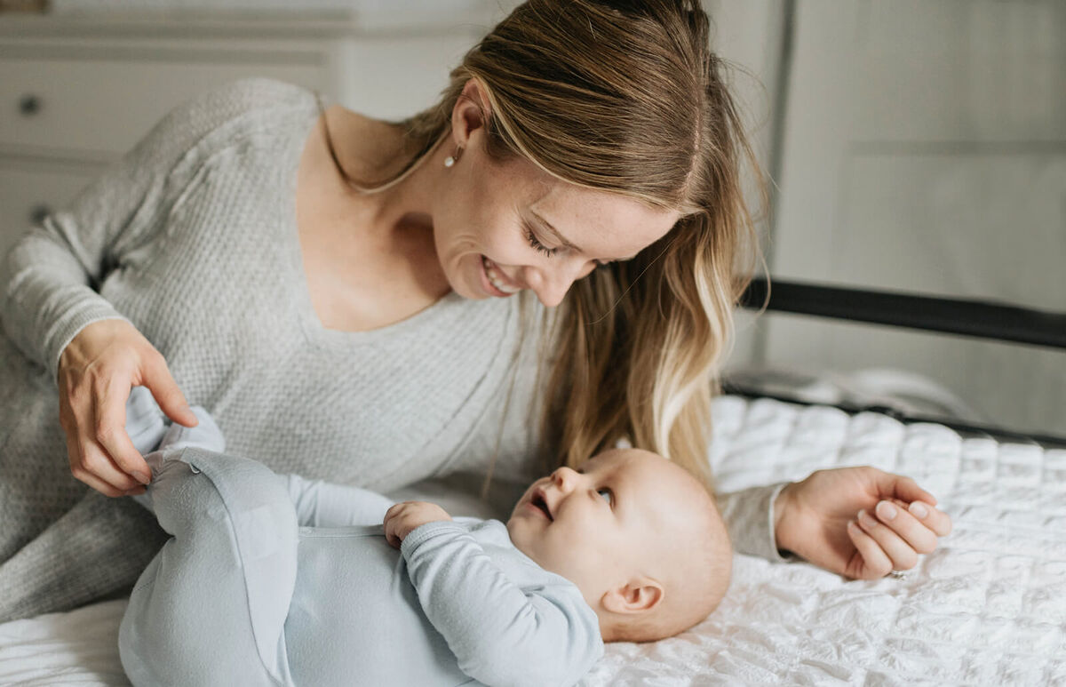 Mother and baby boy smiling at each other in bed