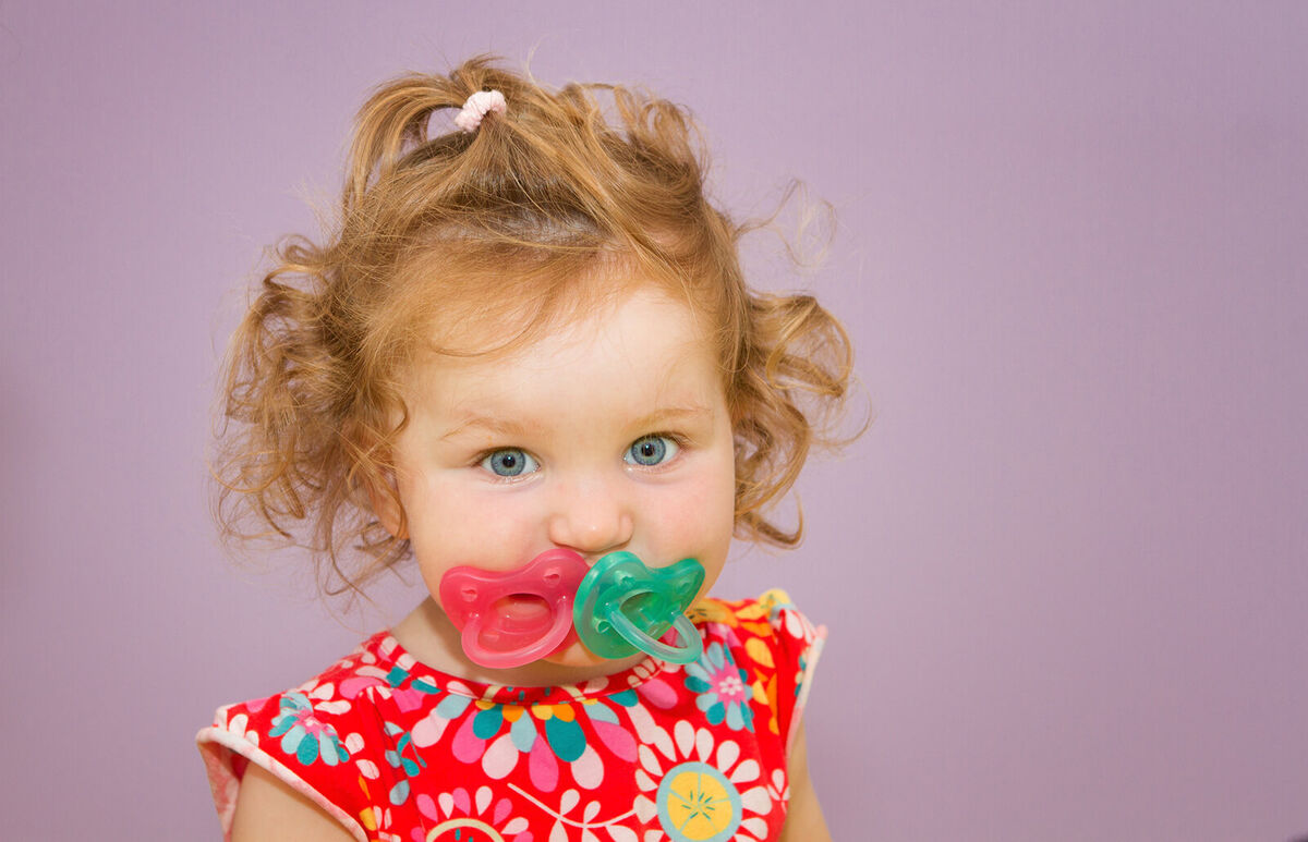 Toddler girl with two pacifiers