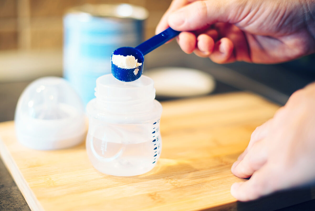Father making baby formula in milk bottle
