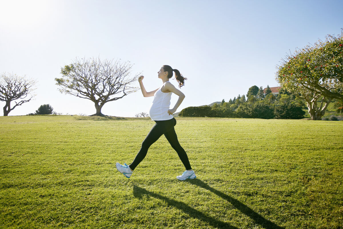 Pregnant woman exercising in field