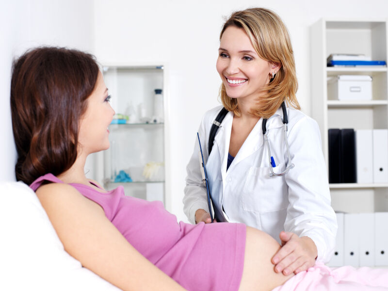 Female obstetrician examining pregnant woman's abdomen