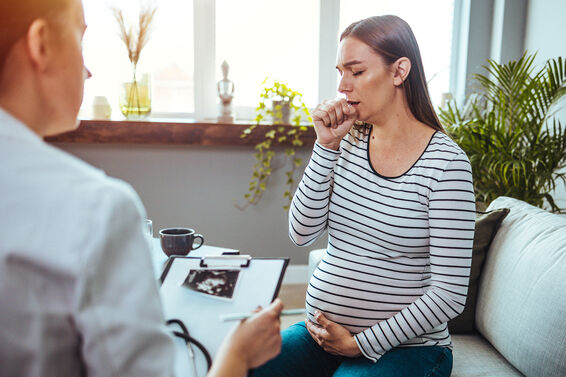 Young pregnant woman on a visit to doctor, coughing