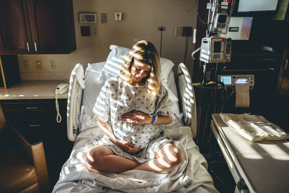 Pregnant woman cradling her belly in the hospital