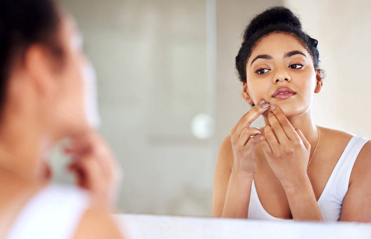 woman squeezing a pimple on her face