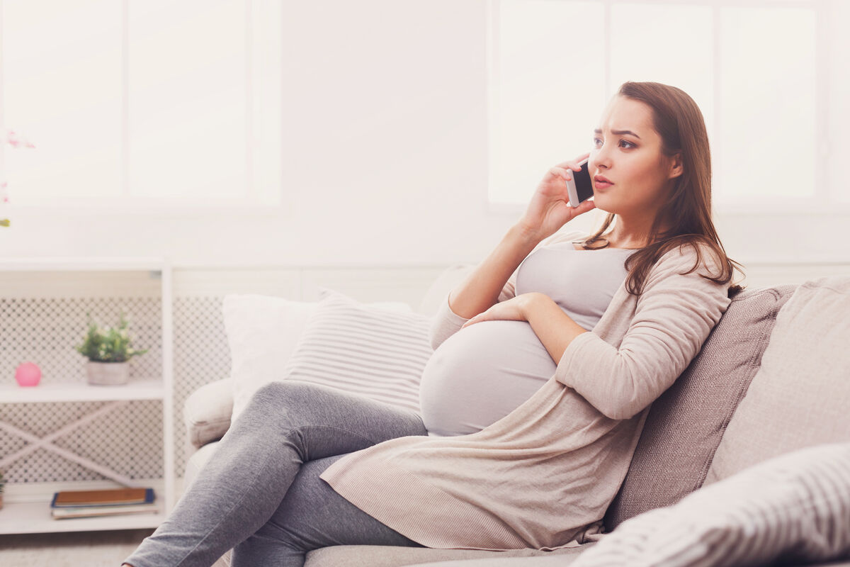 Worried pregnant woman talking on her smartphone